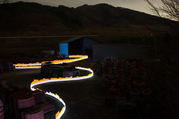 A special light painting technique reveals radioactive contamination at the Sato family's breakwater barrier factory in Iitate. Surrounded by forest and a growing stockpile of waste from decontamination work, the property remains contaminated despite being cleaned up. Here we see radiation levels between 0.22uSv/h and 1.15uSv/h, with yellow showing spots elevated above the government decontamination target of 0.23 uSv/h, and red showing above 1uSv/h. Greenpeace/Greg McNevin